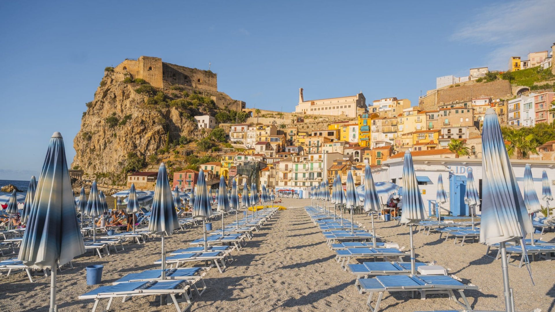 Rows of striped blue beach umbrellas in a picturesque hilltop village, Scilla, Calabria, Italy