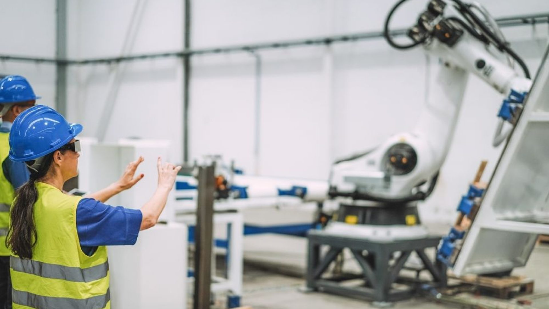 Female worker using futuristic augmented reality glasses inside robotic factory while working with ai machines - Industrial and technology concept - Focus on woman helmet